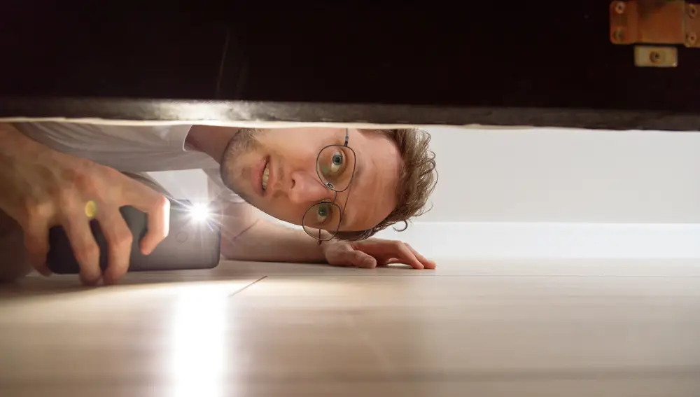 Hombre mirando debajo de cama